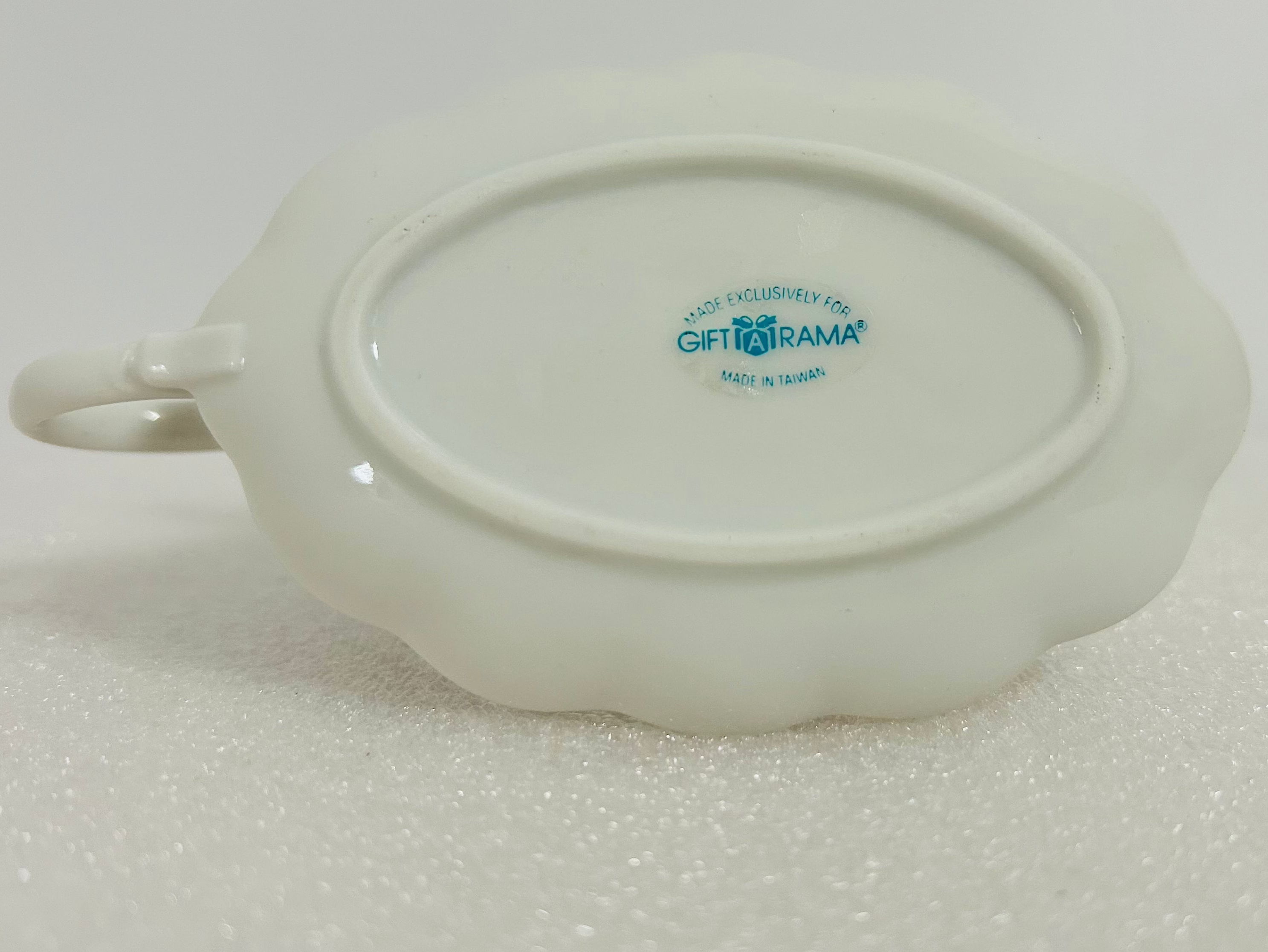 White ceramic dish with a logo on a light gray background